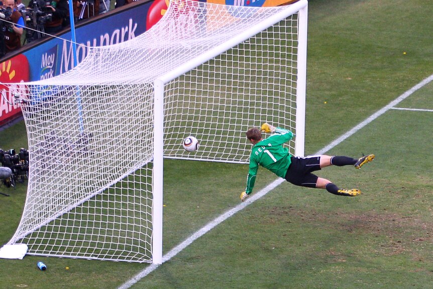 A keeper dives to save a ball that appears to be over the goal-lline