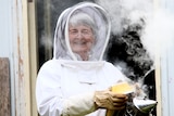 An elderly woman in a bee keeping suit