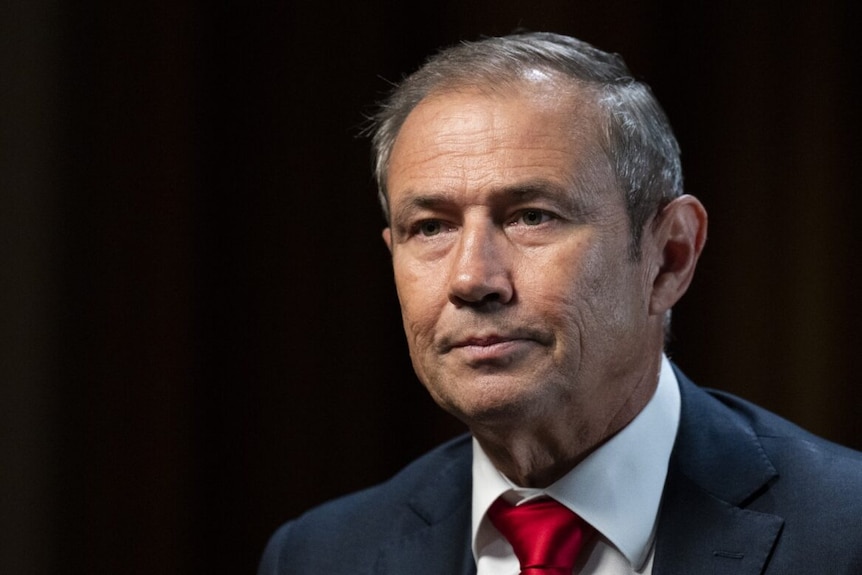 A close up shot of Premier Roger Cook in a navy suit and red tie.