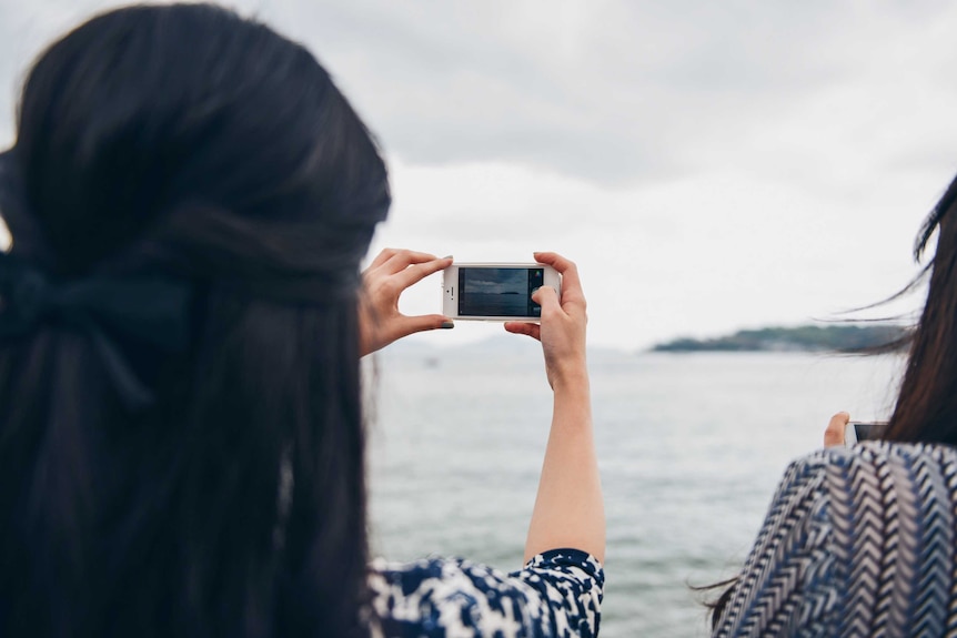 A woman takes a photo on her mobile phone.