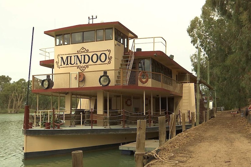 A large pale yellow paddleboat with seats on the lower duck and the steering wheel visible through window at the top.