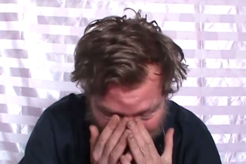 A man crying with his hands over his face