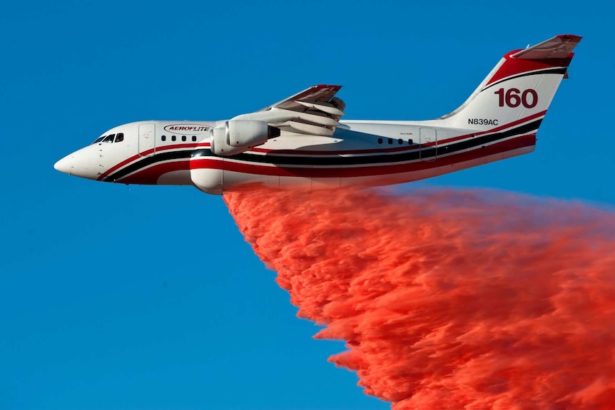 Firebombing plane drops fire retardant on a fire