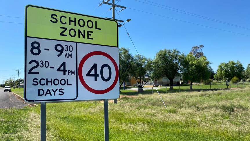 A school zone sign in front of a brick building.