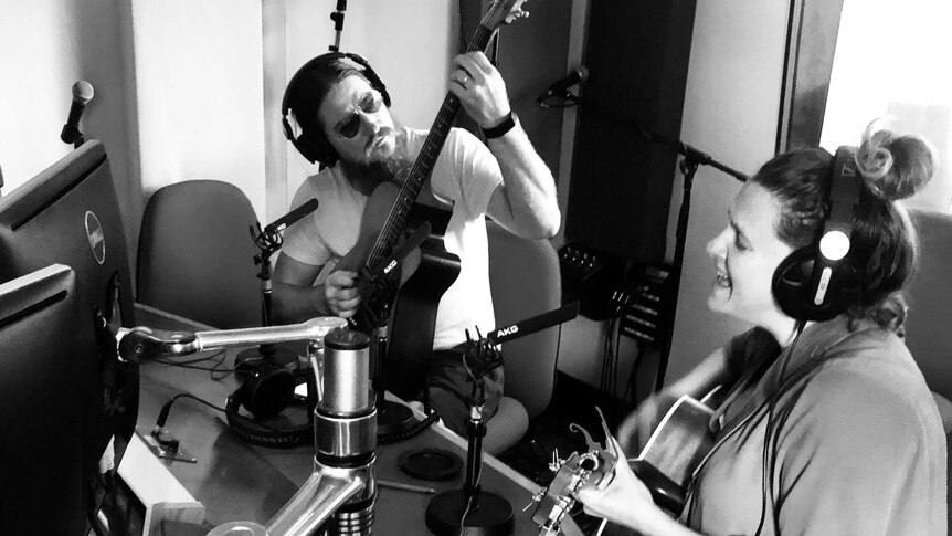 Adam Eckersley and Brooke McClymont playing guitars and singing in the studio.