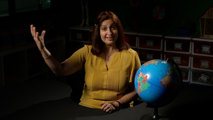 Female teacher sits beside earth globe