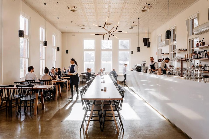 Diners at a cafe and bar inside a heritage building fitted out with modern decor and appliances.