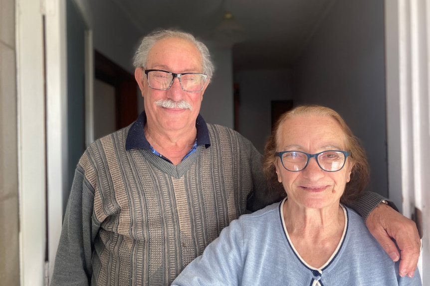 A senior Italian couple. The man's arm is around the woman.