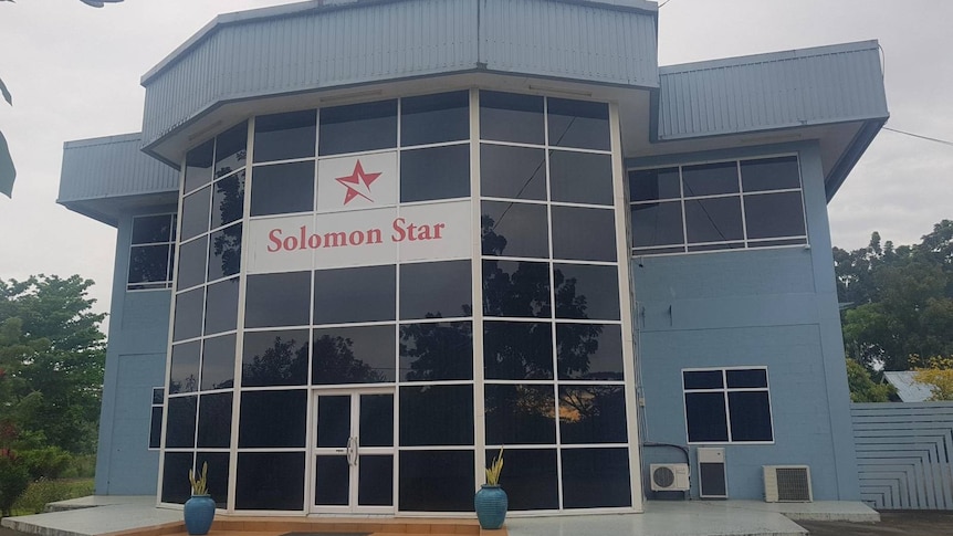 A blue grey building with black windows across the front and a sign reading: "Solomon Star".