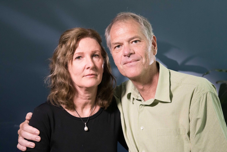 A husband and wife look seriously at the camera.