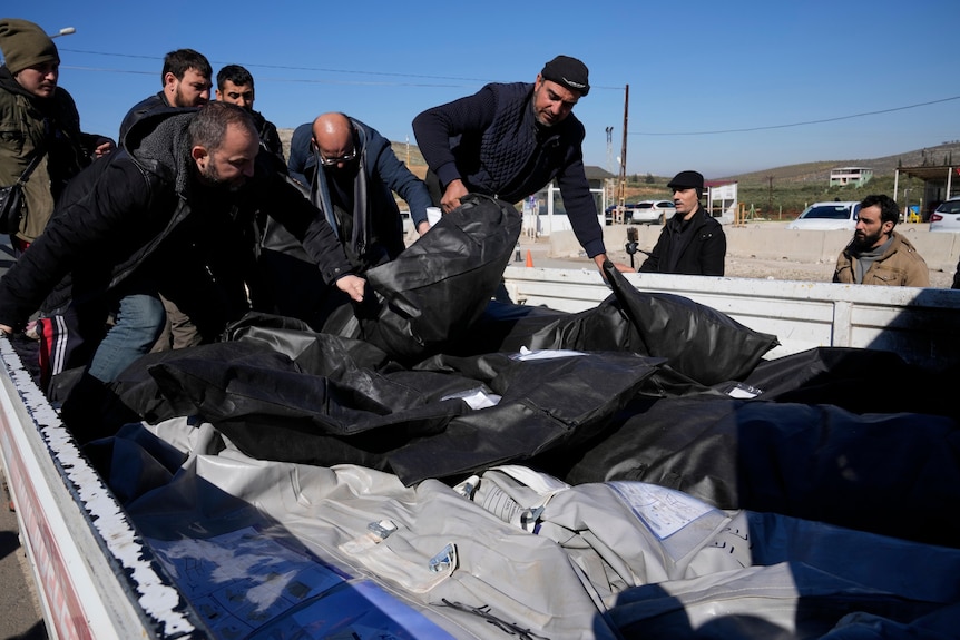 Men load the bodies of Syrian victims on to a truck to transfer to Syria at the Turkish-Syrian border.