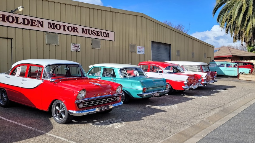 colourful vintage cars lined up outside a museum