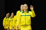 A smiling netballer walks out onto court ahead of her team before a Test match.