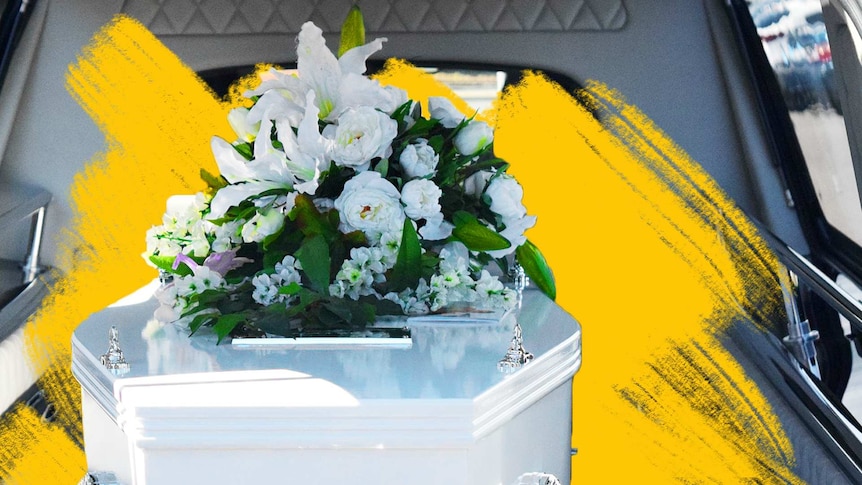 White coffin with white bouquet in a hearse.