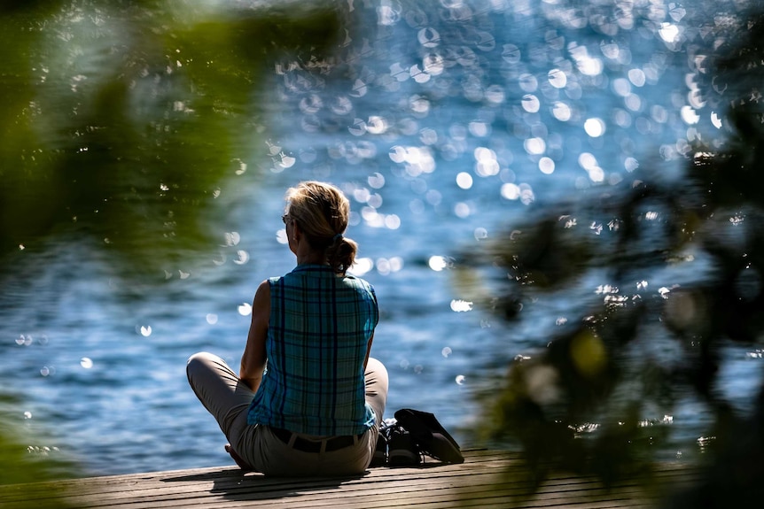 A woman looks out over the water in the sun.