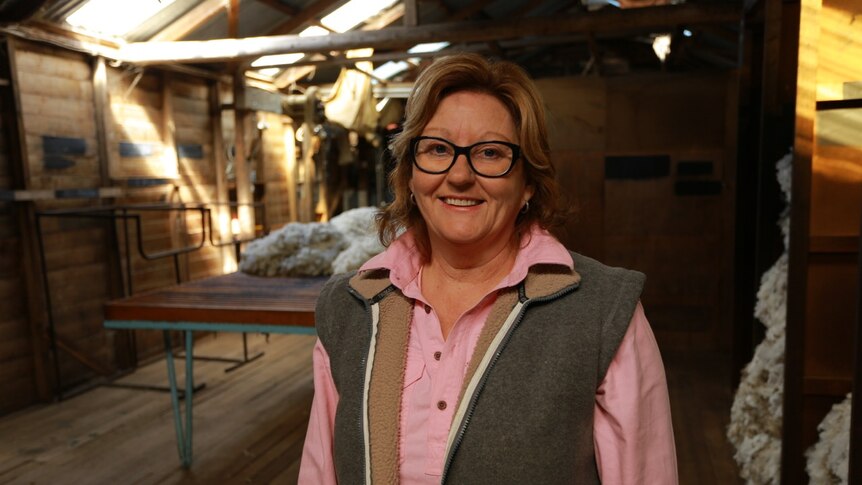 Inside a woolshed with Marie Boadle. Sunlight through skylights falls on fleece on wool table