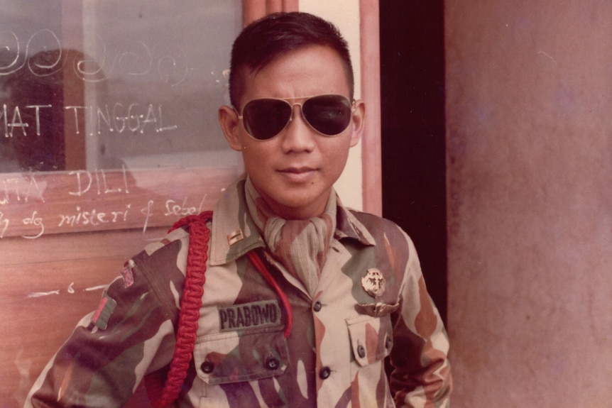 A young man wearing aviator sunglasses and camouflage uniform with PRABOWO on breast pocket