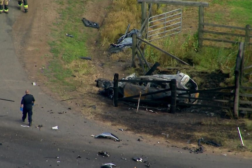 Police at the scene of a car crash at Brightview, near Brisbane. Burnt out car to the right of frame