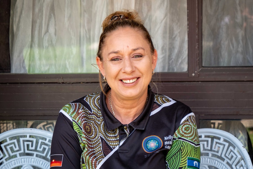 Helen Eason smiling in a polo shirt with Indigenous designs on it.