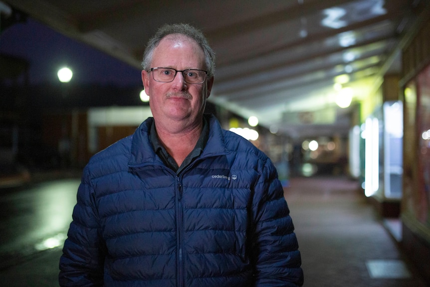 A man wearing glasses and a puffer smiles at the camera.