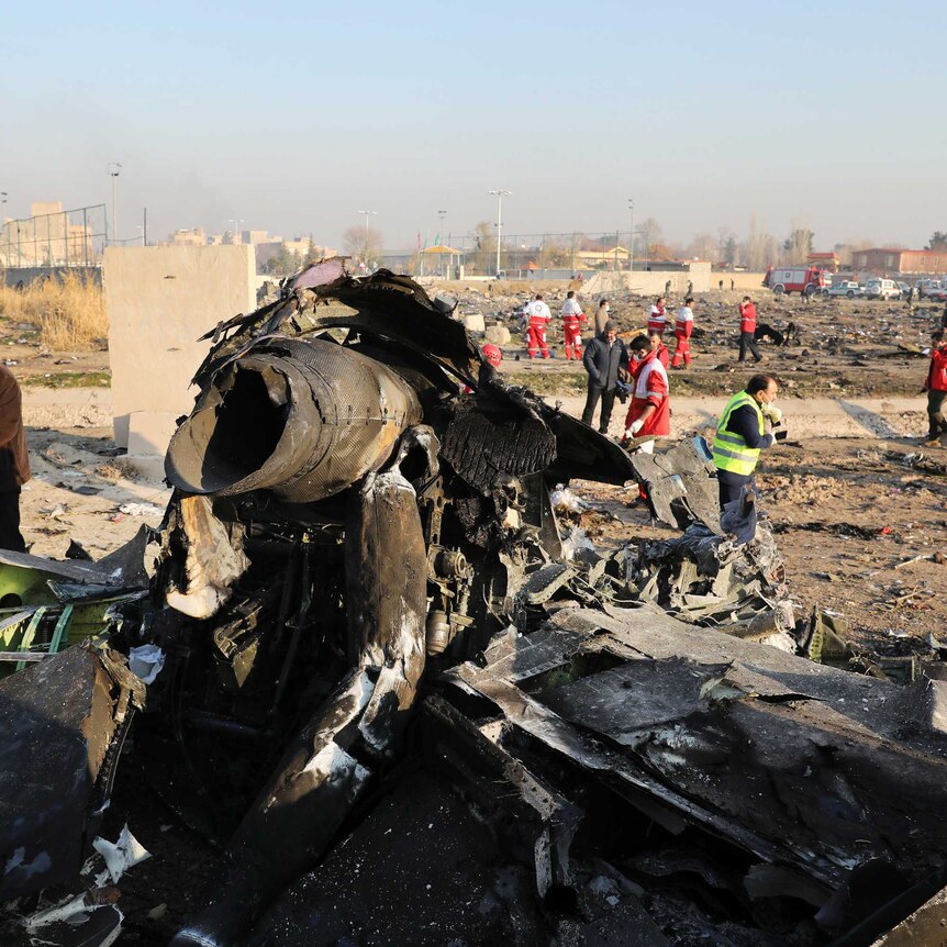 People are seen in the background working as the main piece of wreckage belonging to a Boeing 737 sits in the foreground.
