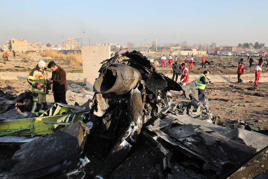 People are seen in the background working as the main piece of wreckage belonging to a Boeing 737 sits in the foreground.