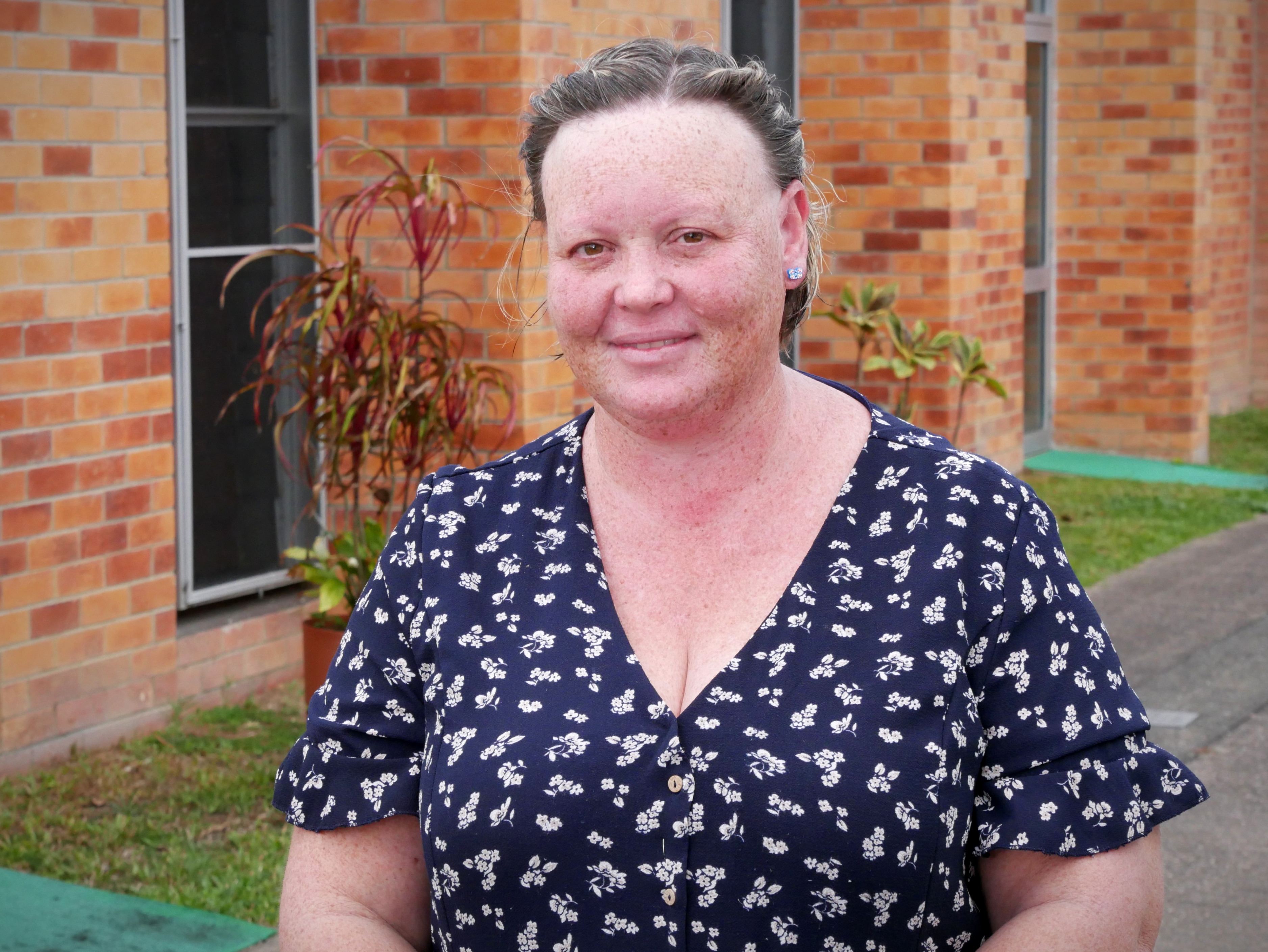 A woman in a floral dress outside a brick building.