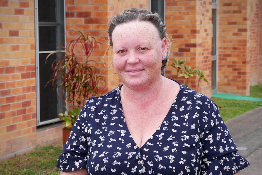 A woman in a floral dress outside a brick building.