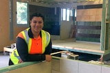 TJ Pamo, a young trainee carpenter, leans on a wall in her hi-vis uniform