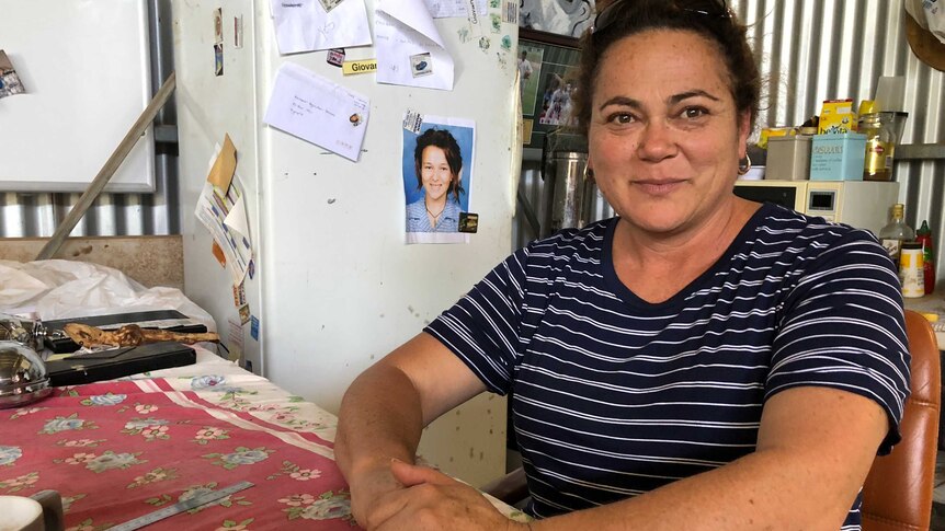 mother sitting on bench with photo of deceased daughter on a fridge behind her