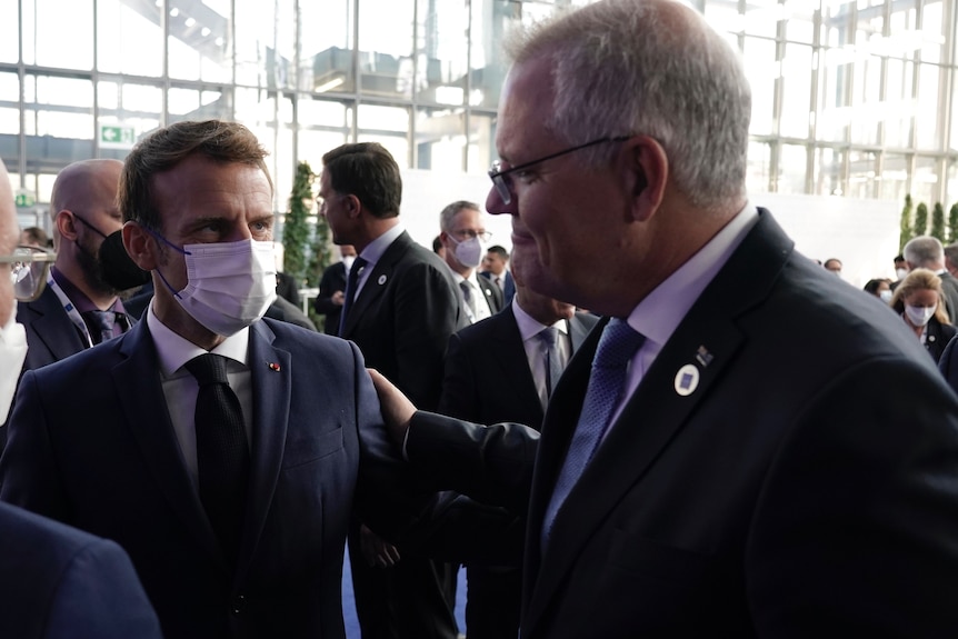 Une photo du président français Macron, qui porte un masque, et de Scott Morrison avec sa main sur l'épaule de Macron.