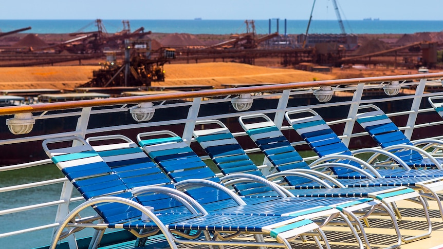 Deckchairs lined up against railing with Port Hedland port in background