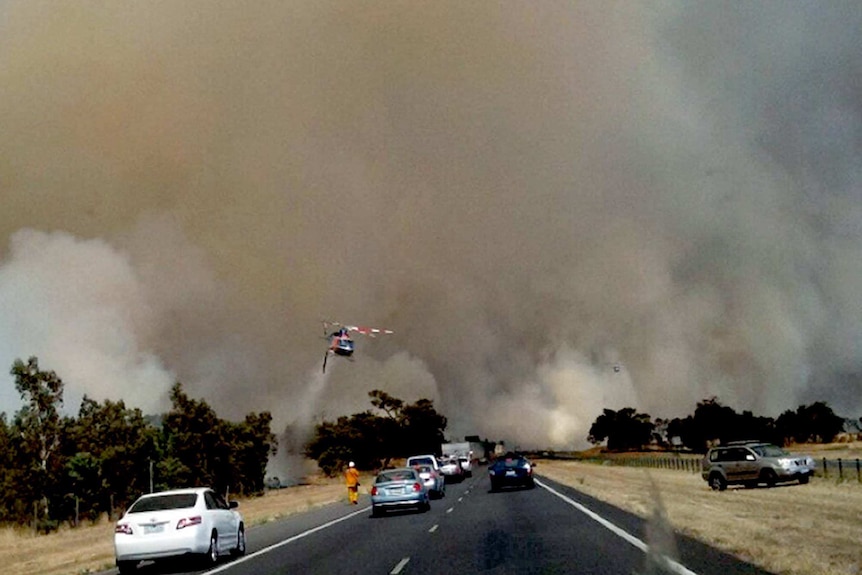 A water-bombing helicopter fights the bushfire burning near Epping