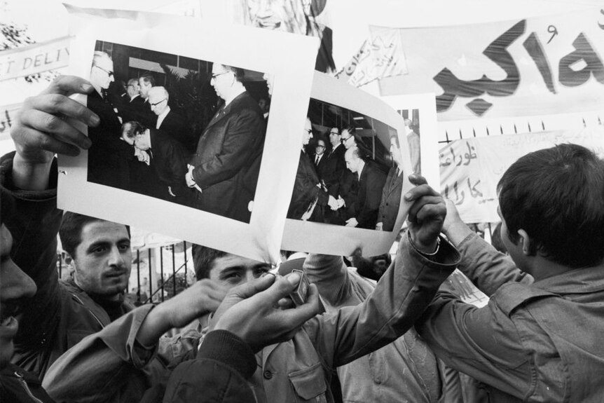 Demonstrators burn pictures of the Shah or Iran.