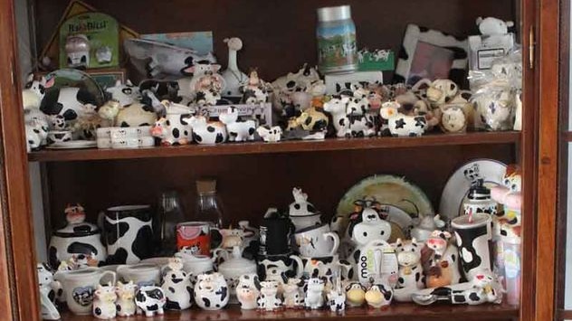 A shelf full of black and white cow ornaments