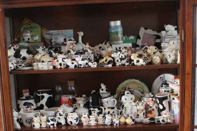 a shelf of black and white cow ornaments
