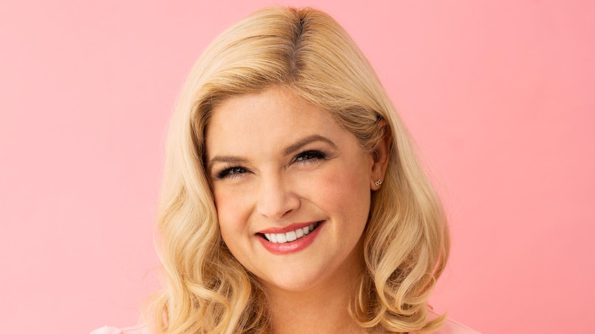 A professional portrait of Lucy Durack, who has long blonde hair and is wearing a light pink dress.