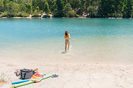 A woman in a bikini shot from behind at a lake.