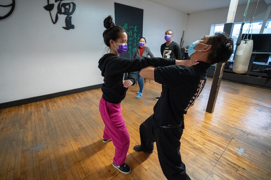Woman and man both wear face masks during a martial arts class.