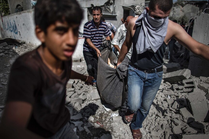 Men pull a body from the rubble in Gaza