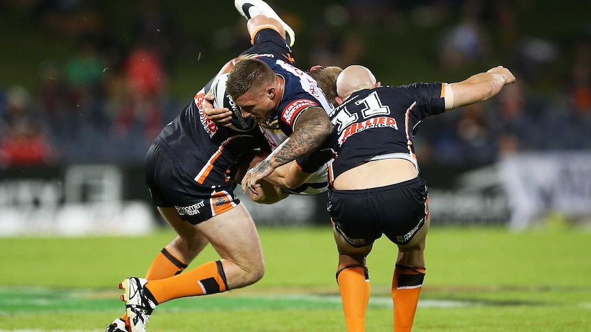 The Cowboys' Tariq Sims is met solidly by the Wests Tigers defence.
