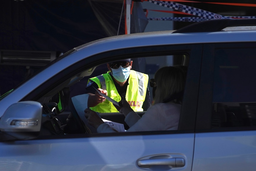 A police officer checks a driver's border pass at Coolangatta