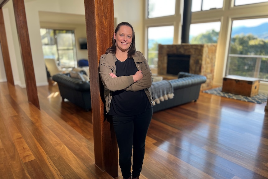 Woman stands against a pole in a luxury home.