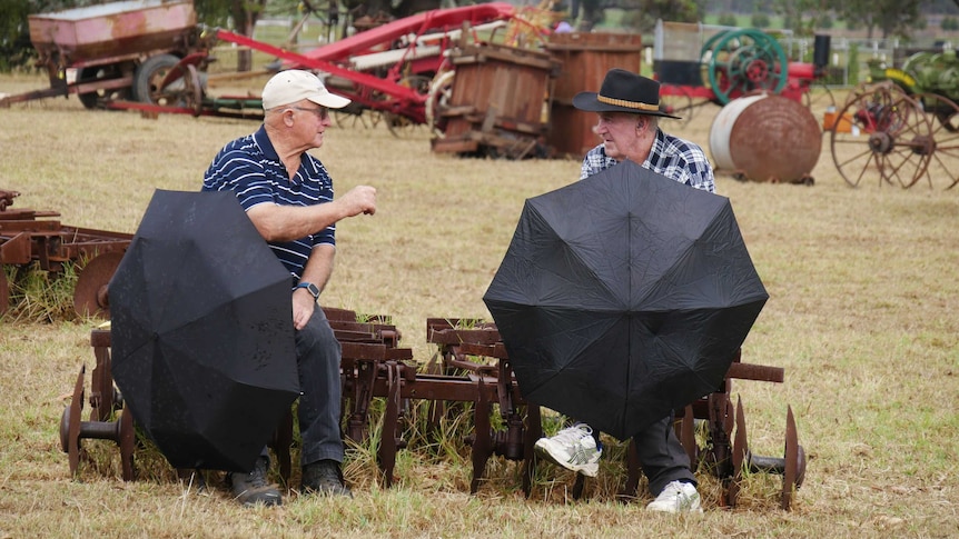 Two men sitting with umbrellas