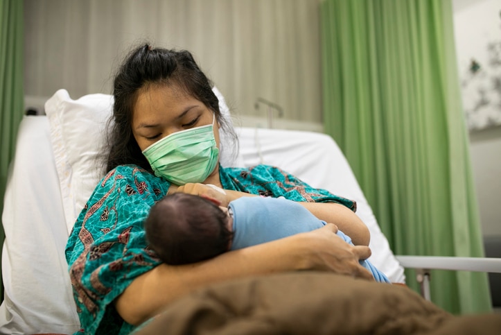 Mother holds baby in hospital bed