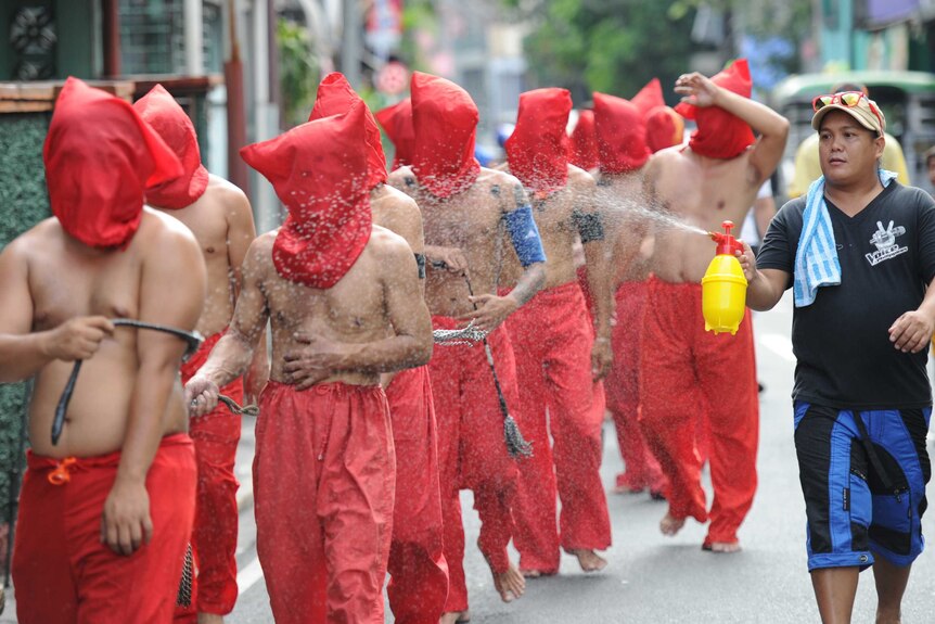 A man sprays penitents with water to cool them down