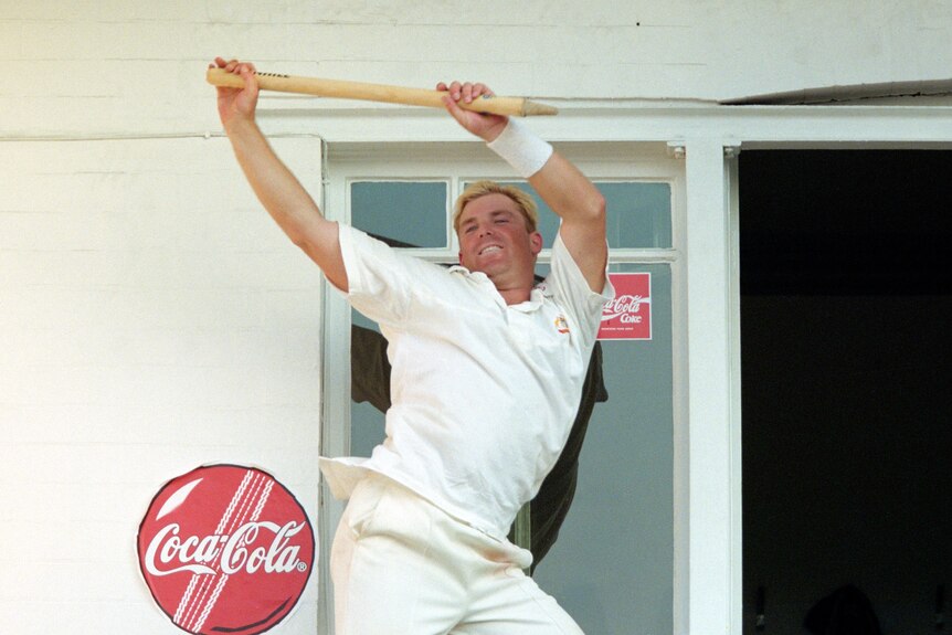 Shane Warne cavorts with a stump on a balcony