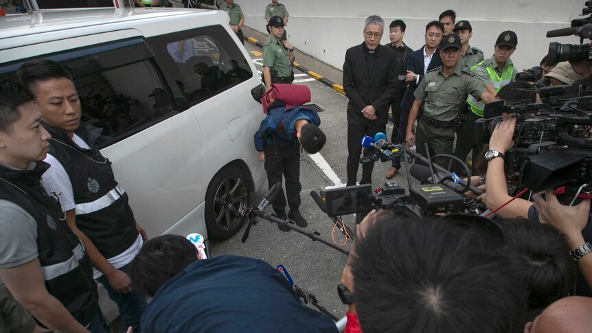 Chan Tong-kai bows while surrounded by media and police after being released from prison.