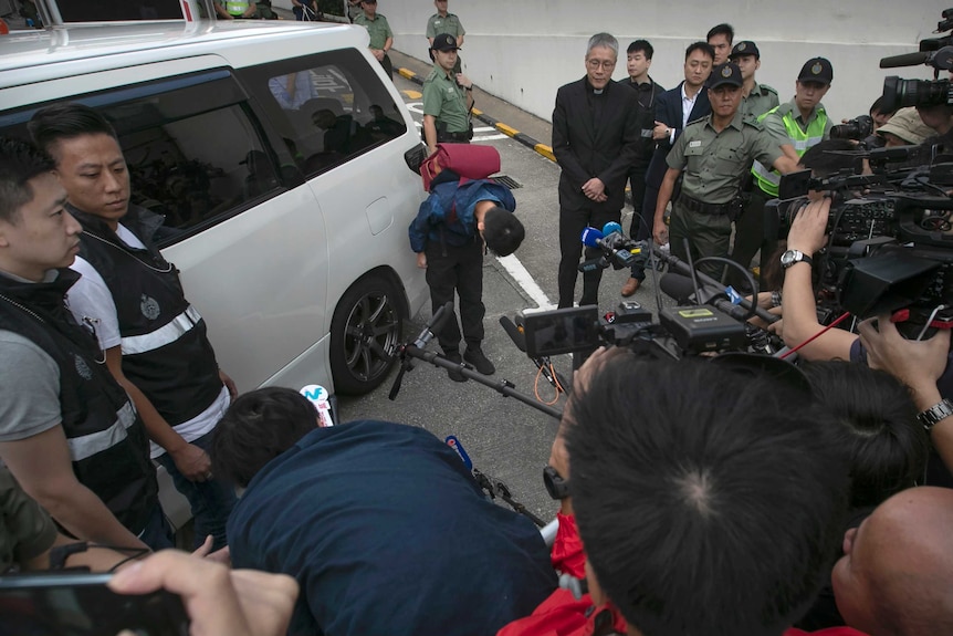 Chan Tong-kai bows while surrounded by media and police after being released from prison.