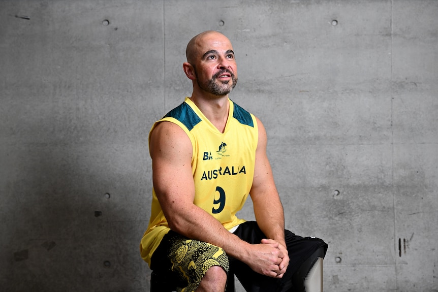 Australian wheelchair basketballer Tristan Knowles wearing a green and gold singlet sits and poses for a photo.
